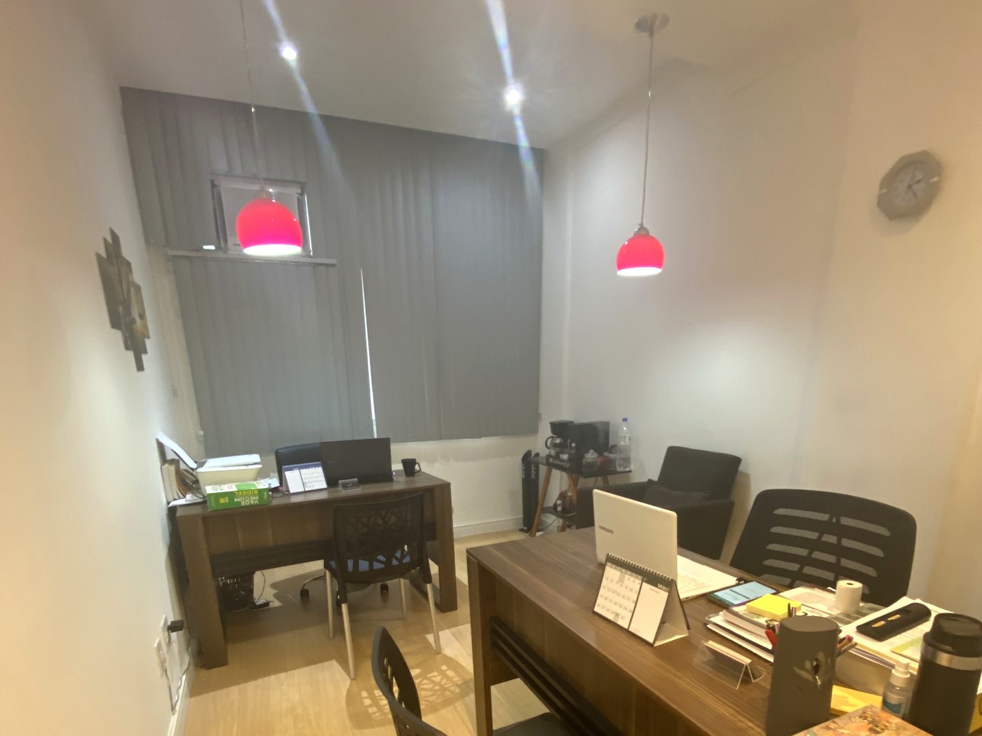 Foto real do ambiente de trabalho do escritório, com mesa, cadeiras pretas e iluminação aconchegante